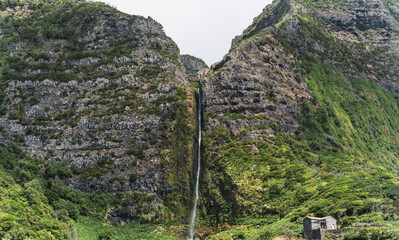 big waterfall in the middle of the rocks with a house underneath