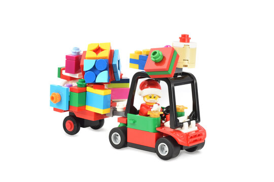 Lego minifigure of Santa Claus with gifts drives a car isolated on white background. Editorial illustrative image of popular plastic toy constructor.