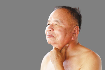 Elderly man touches his neck with his hands because of a sore throat caused by various viral infections such as the common cold and coronavirus. Health care concept.