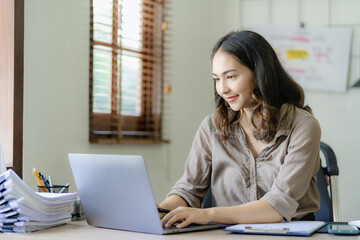 Asian businesswoman handling accounting tasks Accounting group meeting online and using laptop computer Professional confident employees in the office