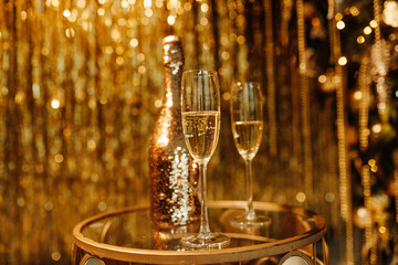 Champagne bottle and glasses against luxury glow golden rain decoration expensive holidays party