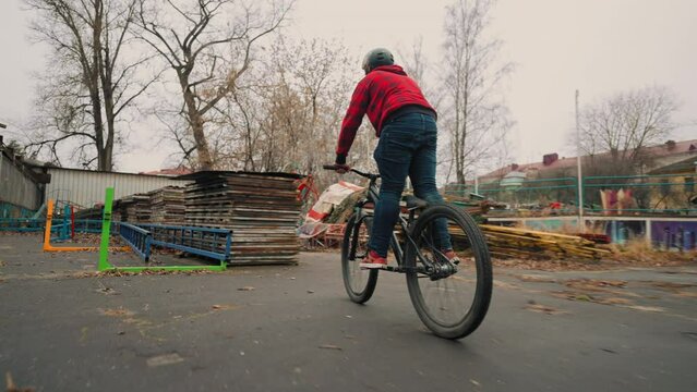 skilled teen boy is showing extreme tricks on bike in park, teenger rider is riding bmx bicycle