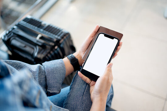 Traveler showing empty space on phone in hand with suitcase in airport terminal