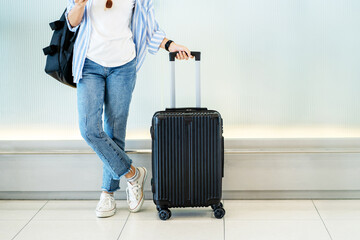 Asian woman teenager using smartphone at airport terminal standing with luggage suitcase and...