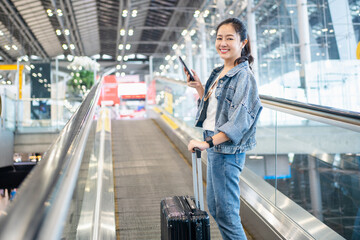 Asian woman traveler walking dragging a suitcase to gate in airport - Powered by Adobe