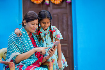 indian rural woman and his little daughter using smartphone.