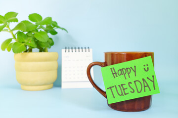 Welcome, hello and happy Tuesday concept. Selective focus of coffee cup with green paper note and written message.