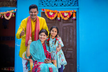 Fototapeta na wymiar Happy indian farmer with his wife and little girl showing thumps up