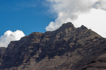 View of Caleta de Famara from the bungalows. Houses. Desertic landscape. Beach with waves, village and mountains in the background. Clear sky. Famara Beach, Lanzarote, Canary Islands, Spain.