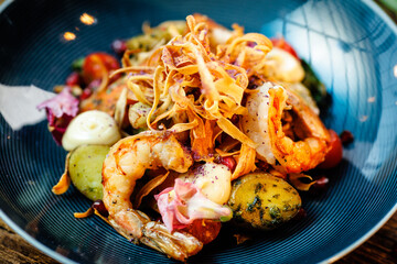 Warm salad with Argentinian king prawns. Almond potato, mini romaine lettuce, carrot, cherry tomato, pesto, black root chips, caramelized walnut, beet balsamic. Food served in modern restaurant