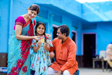 Indian little girl showing medal with parents.