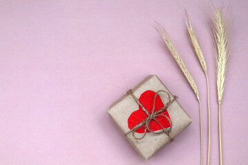Craft gift box with red heart and craft ribbon on pink background. For celebrate. Valentines day conception.