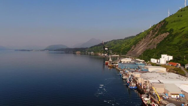 Port Harbor at Bottom of Cliff Mountain in Juneau City Alaska in Beautiful Summer Day, Aerial Panoramic View of Dock Boats and Wind Turbines on Top of Mountain, Alaska Landscape