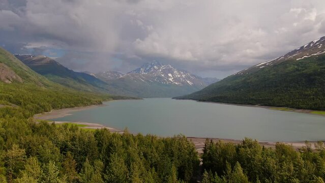 Alaska Lakeside Landscape On Cloudy Summer Day, Beautiful Panoramic of Wild Nature, Valley Lake With Green Forest and Mountains Around - Aerial Static Shot