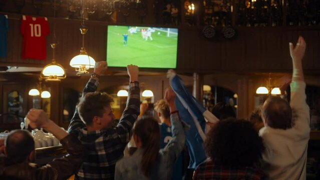 Soccer Club Members Cheering for Their Team, Playing in an International Cup Final. Supportive Fans Standing in a Bar, Cheering, Raising Hands and Shouting. Friends Celebrate Victory After the Goal.