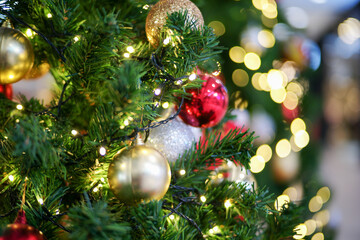 Selective focus on the golden ball decorated on the Christmas tree with the bokeh lights in background. Party and celebration in Christmas festival