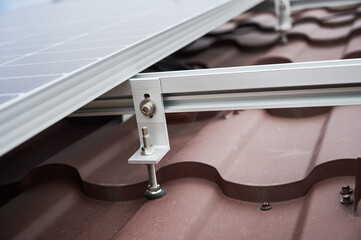 Close up view of mountain clamp of solar photovoltaic panel system on house roof.