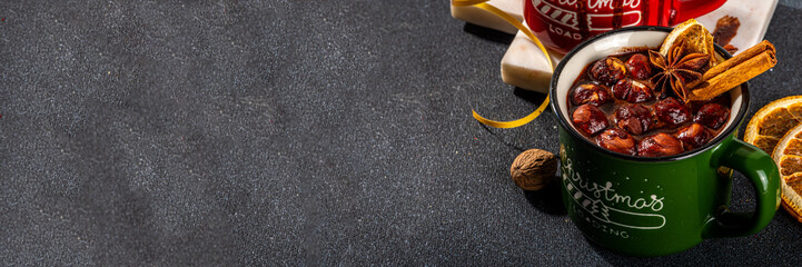 Homemade hazelnut  hot chocolate, dark winter cocoa drink with a lot of nuts, chocolate and spices, in cozy winter Christmas red and green cups, with Xmas New Year decorated background copy space