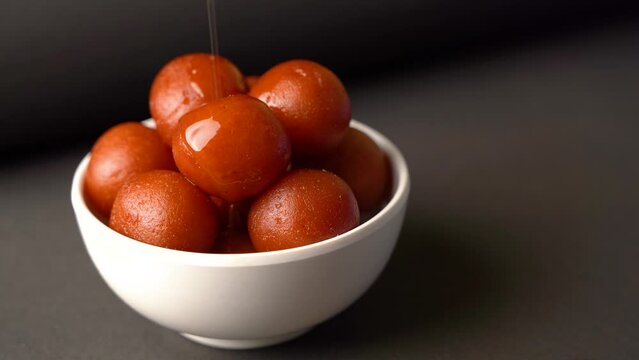 Sweet Gulab Jamun served in bowl, Famous Indian dessert sweets isolated over black indoor studio background