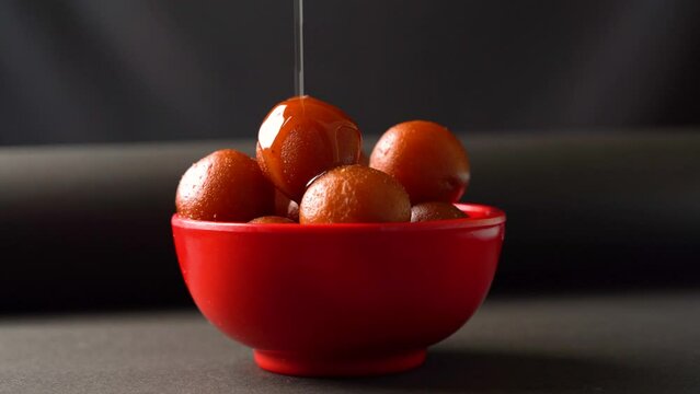 Sweet Gulab Jamun served in bowl, Famous Indian dessert sweets isolated over black indoor studio background