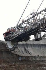 Fototapeta premium Bucket-wheel excavator during excavation at the surface mine. Huge excavator on open pit mine.