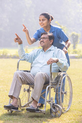 A caring nurse pushing an elderly man in a wheelchair along a pathway.