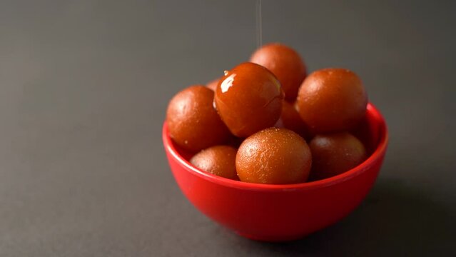 Sweet Gulab Jamun served in bowl, Famous Indian dessert sweets isolated over black indoor studio background