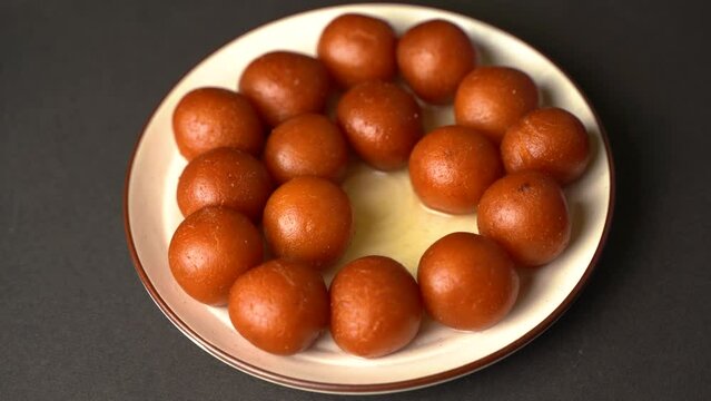 Sweet Gulab Jamun served in a plate, Famous Indian dessert sweets isolated over black indoor studio background