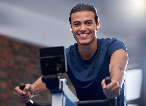 Man, fitness and cycling at the gym for exercise, workout or healthy cardio training. Portrait, happy smile or exercising on stationary bicycle or bike machine for health, wellness or endurance sport