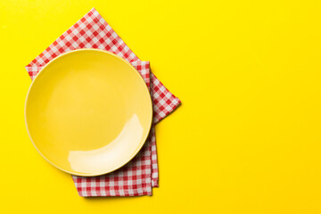 Top view on colored background empty round yellow plate on tablecloth for food. Empty dish on napkin with space for your design