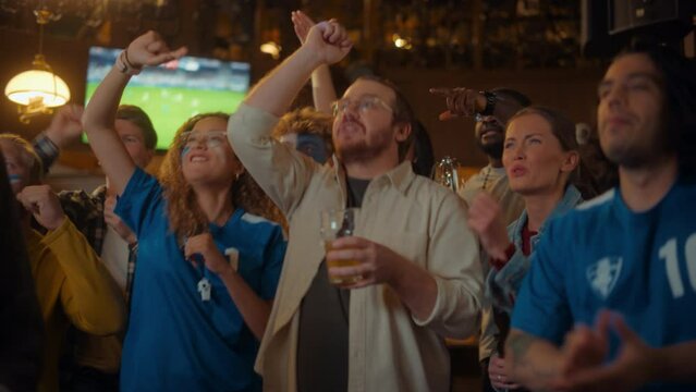 Group of Friends Watching a Live Soccer Match on TV in a Sports Bar. Excited Fans with Painted Faces Cheering. Young People Celebrating When Team Scores a Goal and Wins the Football World Cup.