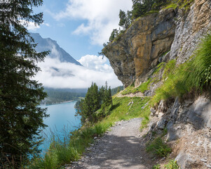 adventurous hiking trail above lake Oeschinensee, under overhanging rocks