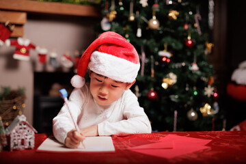 young girl wearing Santa hat was writing letter to Santa at home