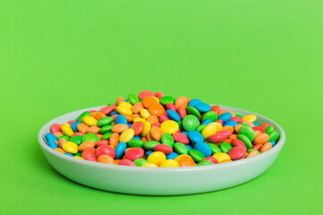 Multicolored candies in a bowl on a colored background. birthday and holiday concept. Top view with copy space