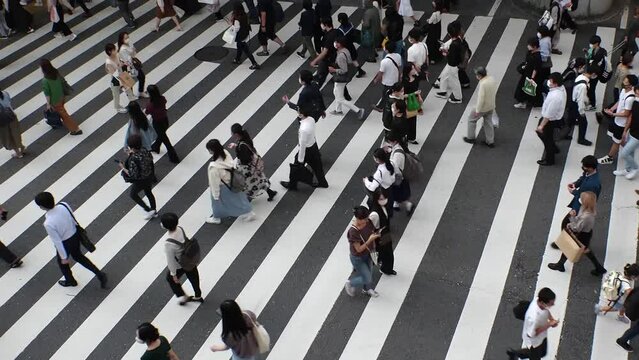 OSAKA, JAPAN : Aerial high angle view of crowd of people walking at zebra crossing near Osaka station in daytime. Commuters at busy rush hour. Japanese lifestyle and business concept. Time lapse shot.