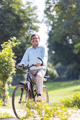 Naklejka premium Senior man enjoying and having fun riding bicycle at park