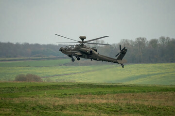 close up side view of British army AH-64E Boeing Apache Attack helicopter (ZM722 ArmyAir606) landing, autumn sky