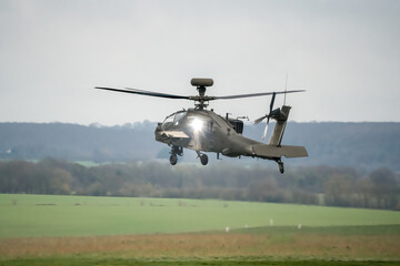 rear three quarter view of ZM722 British army Boeing Apache Attack helicopter (AH-64E ArmyAir606) taking off, autumn sky