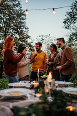Group of elegantly dressed friends having a small boho dinner/wedding outdoors in a garden,...