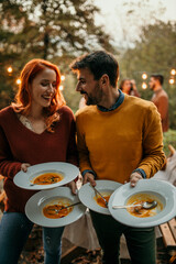 Smiling man and woman removing used soup potage plates and taking them into the kitchen. 