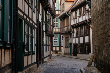 Fototapeta na wymiar Quedlinburg, Saxony-Anhalt, Germany, 28 October 2022: Historic old vintage colored timber frame houses in medieval town, UNESCO World Heritage city, half-timbered home at sunny autumn day, cobblestone