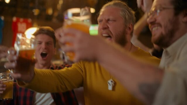Group of Good Friends Enjoying Their Time in a Sports Pub. Three Men Cheering for Their Favorite Soccer Team. Young People Celebrating and Toasting Beer Glasses When Players Score a Goal and Win.