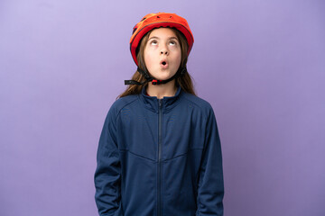 Little caucasian girl isolated on purple background looking up and with surprised expression