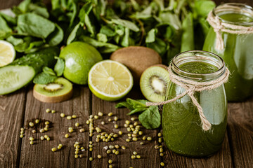 Blended green smoothie with ingredients on the wooden table selective focus. Healthy food. 