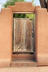 Weathered wood gate to garden in adobe wall in Santa Fe, New Mexico