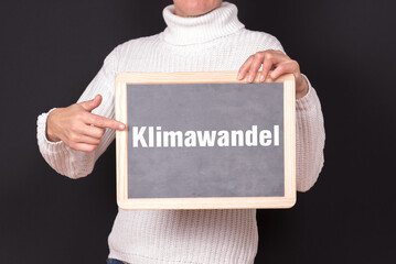 Eine Frau zeigt auf eine Tafel auf der Klimawandel steht