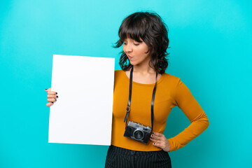 Young photographer latin woman isolated on blue background holding an empty placard and looking it