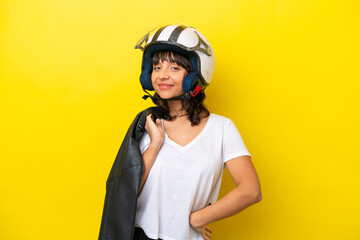 Young latin woman with a motorcycle helmet isolated on yellow background