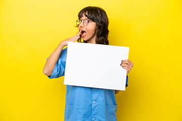 Fototapeta na wymiar Young nurse doctor woman isolated on yellow background holding an empty placard with surprised expression