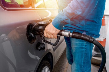 A man at the gas station filling the tank of his car with diesel to the top level before a long...